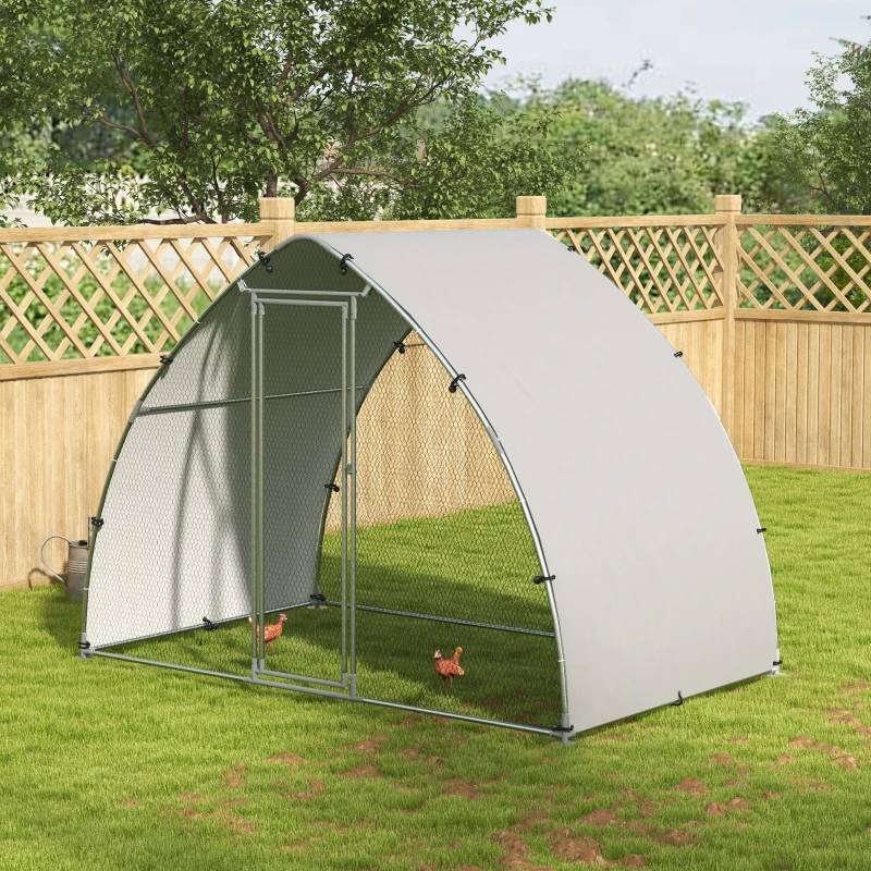 Metal walk-in chicken run with shade cover and hens roaming on grass.
